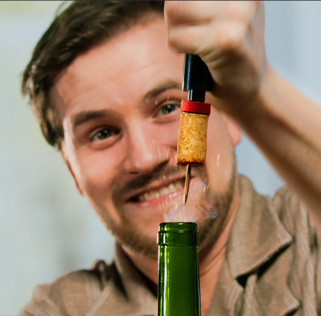 A man opening a wine with the use of a vacuum pump wine opener